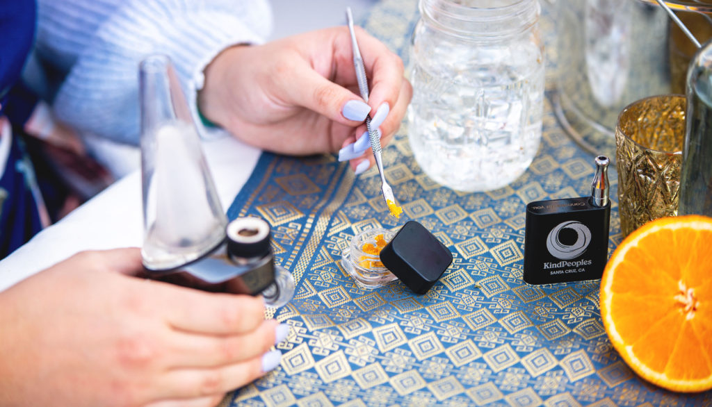 Someone using a dab tool and a puffco peak to smoke a cannabis concentrate. 